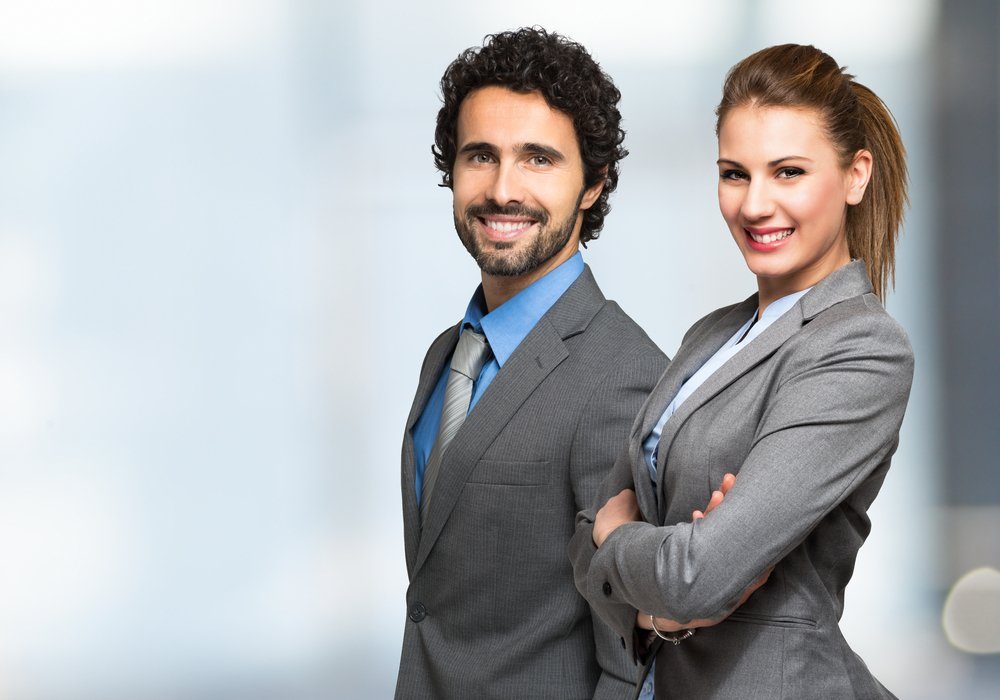 Dois profissionais sorridentes lado a lado em ambiente corporativo